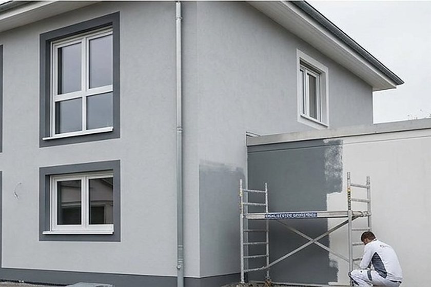 Fassadenanstrich am Anbau, Handwerker arbeitet vom Rollgerüst aus