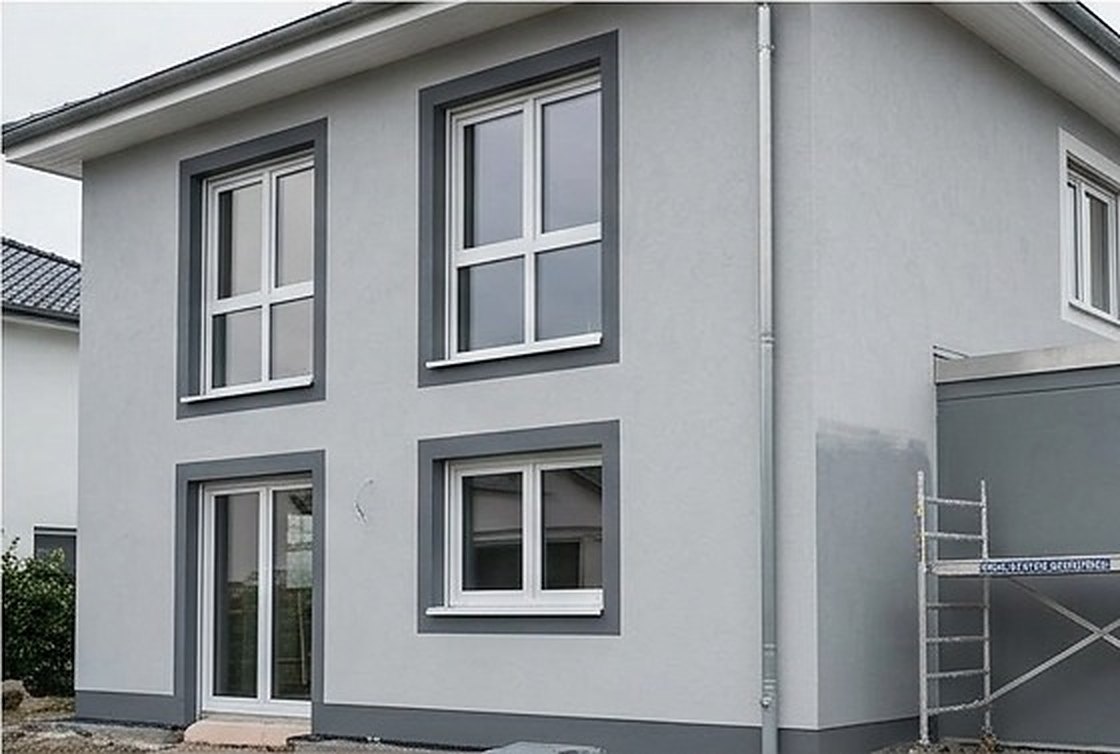 Wohngebäude mit neu gestrichener Fassade, im Hintergrund ein Gerüst am Anbau